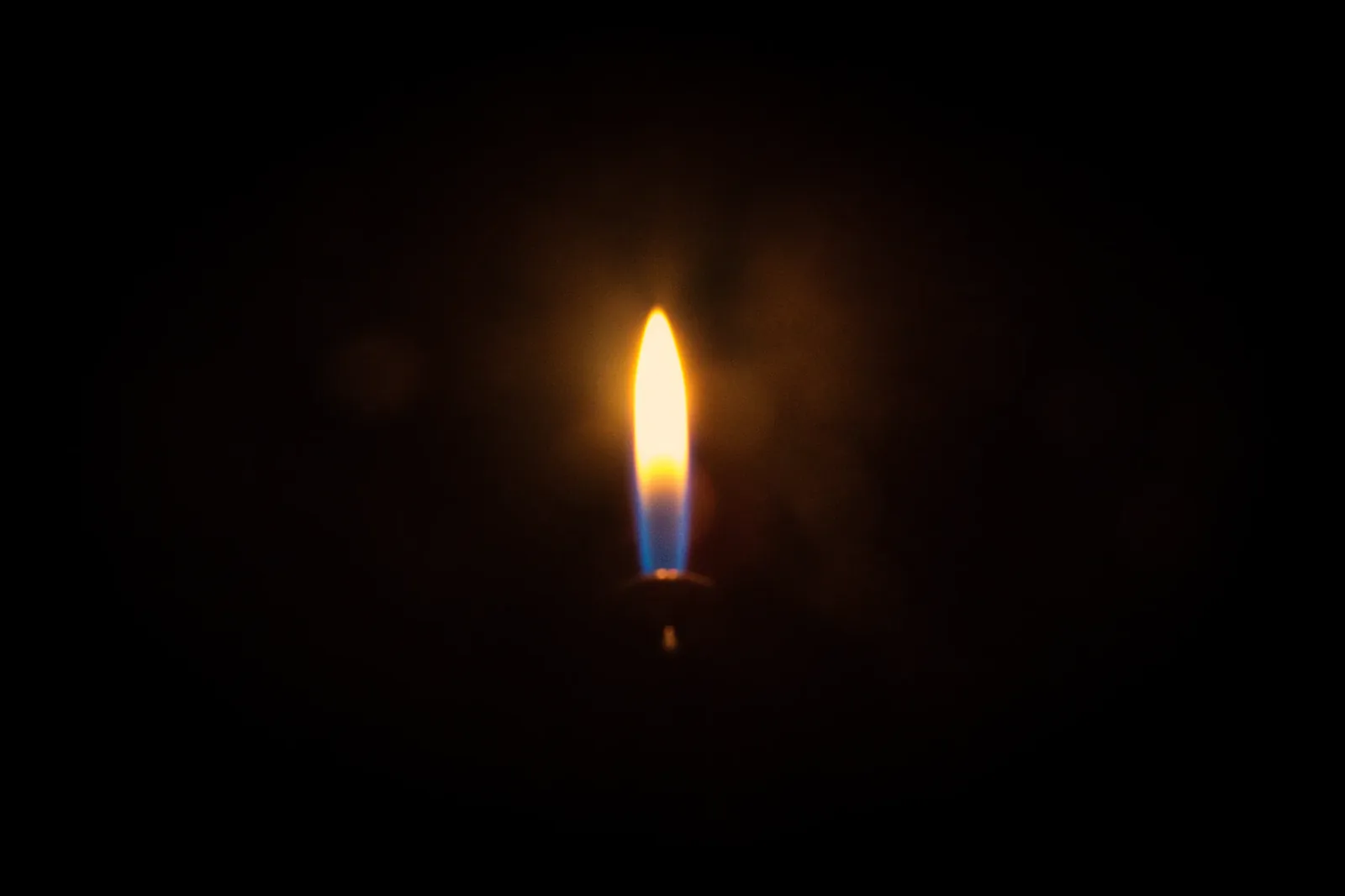 A single candle flame in the dark
