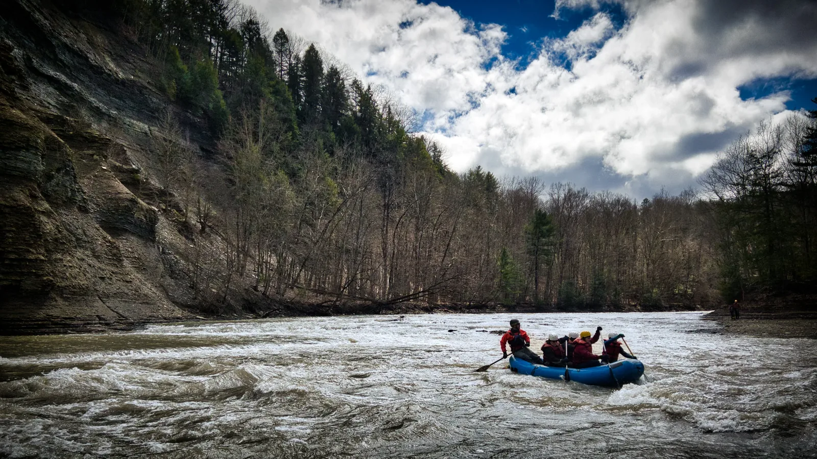 A raft on the river through a wooded canyon