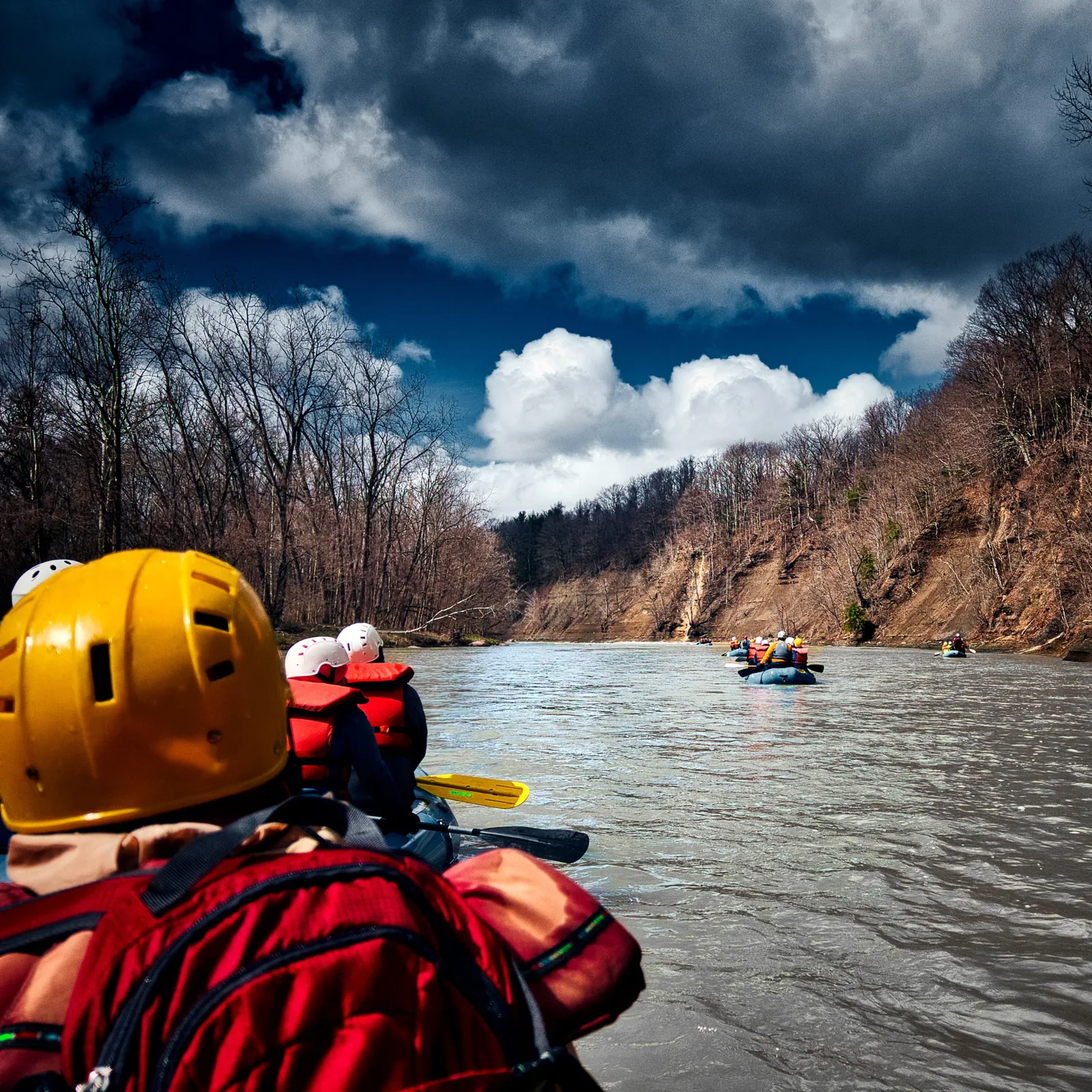A paddler in gear looking downriver under a dramatic sky