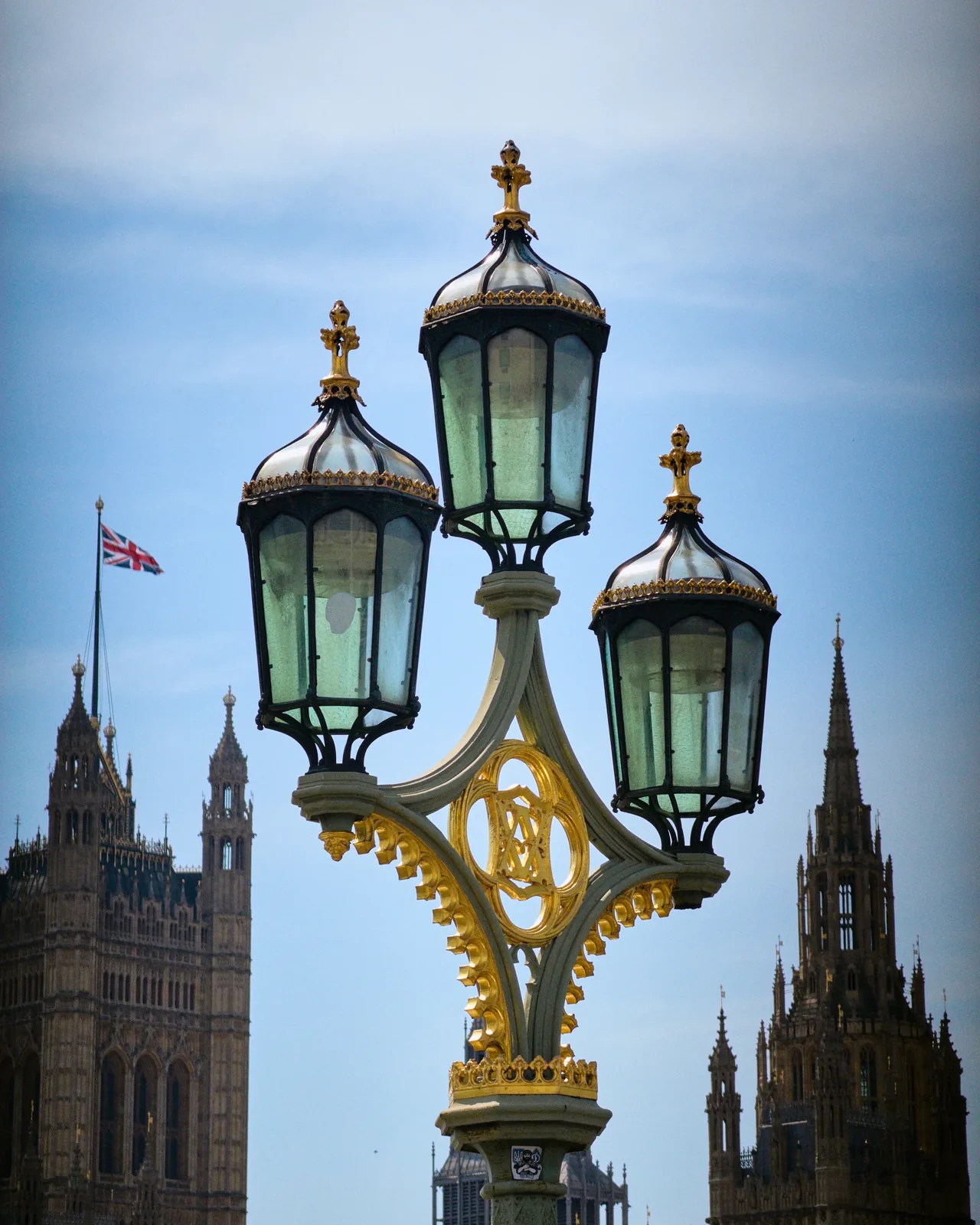 An ornate triple lamp post on Westminster Bridge, with the Houses of Parliament and a Union Jack beyond