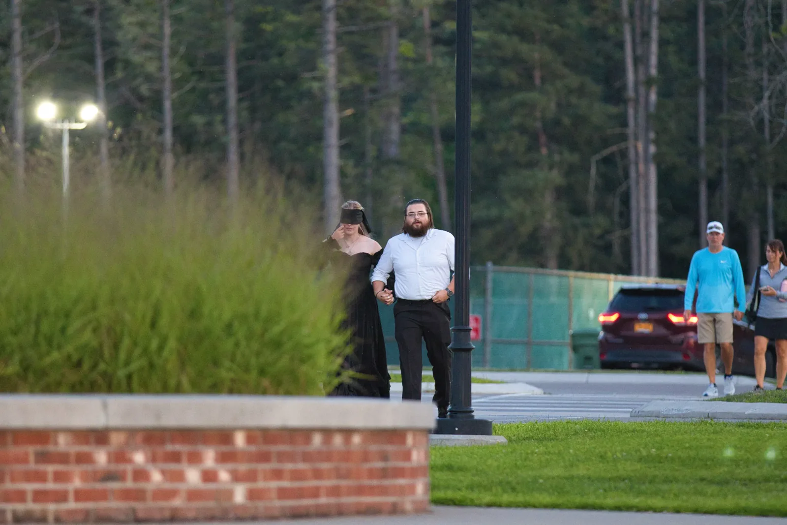 A couple walking arm in arm toward a hilltop overlook at dusk